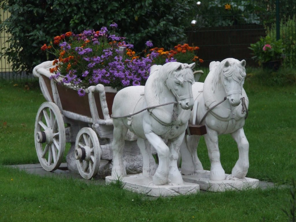 kitscherig beeld in een voortuin: twee paardjes met een kar
